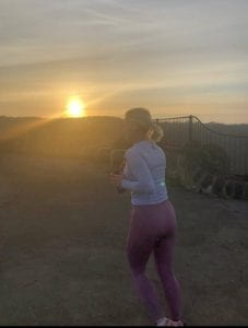 A lady running with the sun setting behind her